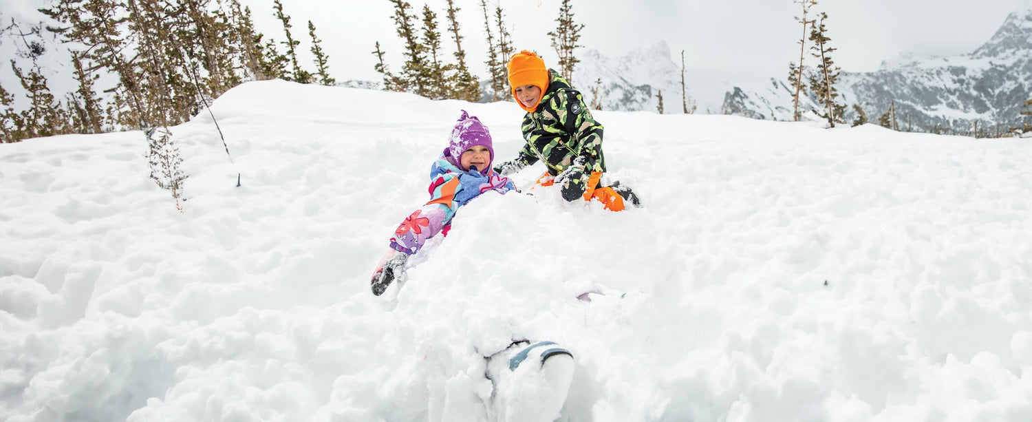 Two kids playing in the snow wearing Obermeyer.