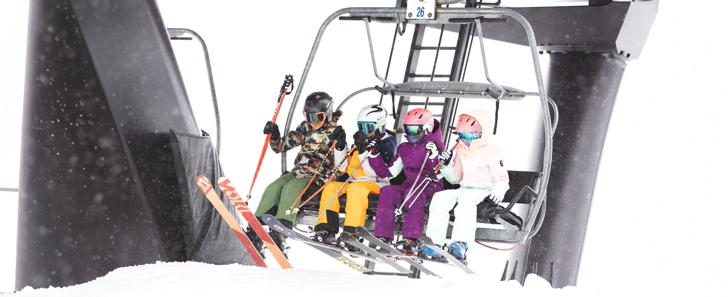 A group of teen skiers getting off of a ski lift while wearing Obermeyer.