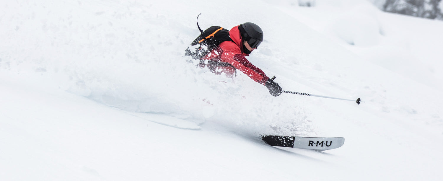 Skiier blowing fresh powder wearing an Obermeyer highlands shell jacket.